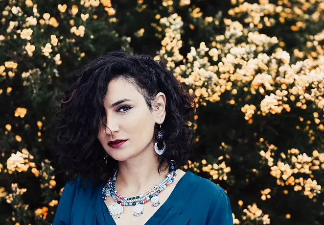 Portrait of Ruba Shamshoum among blossoms